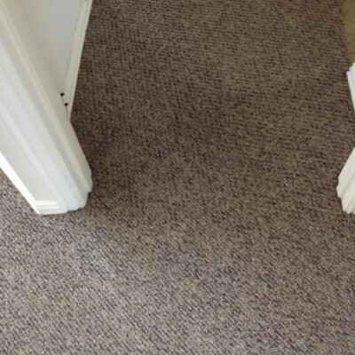 Carpeted hallway with two open doorways, one on the left and one on the right. The carpet is a greyish-brown color.