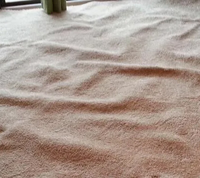 A carpet with noticeable ripples and uneven areas in an indoor room near a glass sliding door.