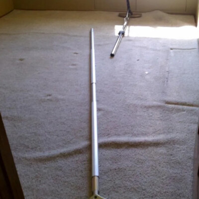 A partially empty carpeted room with tools for stretching carpet laid out on the floor.