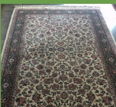 A large, rectangular Persian rug with intricate floral patterns and a dark border, laid out on a floor.