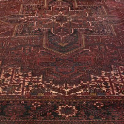 A richly patterned, dark red Persian rug with intricate geometric and floral designs covering its entire surface.