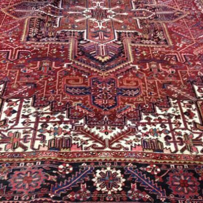 A richly detailed Persian rug with intricate geometric and floral patterns in shades of red, blue, and cream.