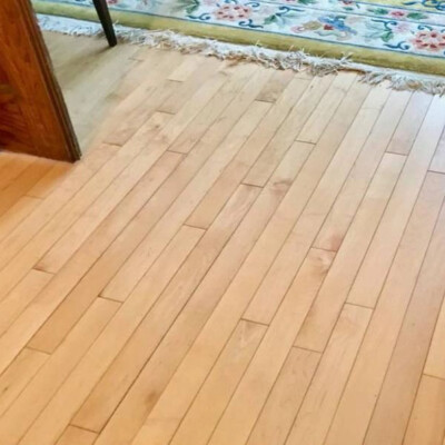 A hardwood floor transitions to a floral-patterned, fringed rug in the doorway.