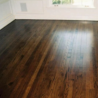 Room with dark wooden floors, wainscoting on the lower walls, and a large window allowing natural light to enter.